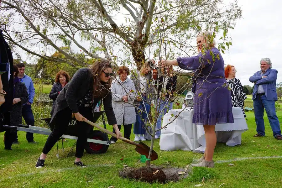 A woman planting a memorial tree at Mornington Green Living Legacy Gardens