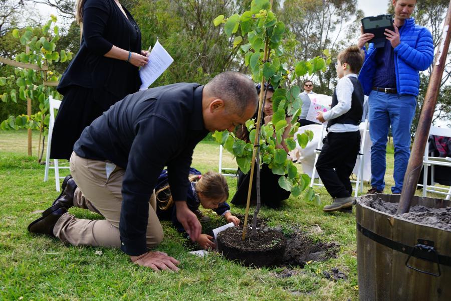 A man and his daughter bury ashes under tree